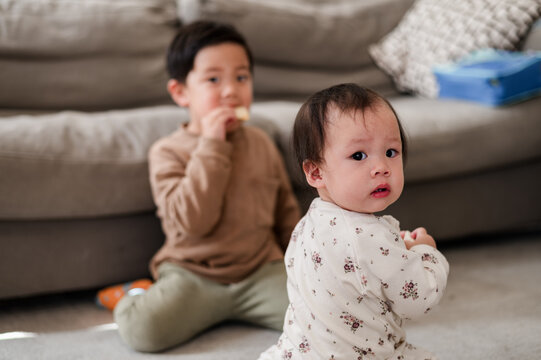 Asian baby girl sitting on carpeted floor looking back