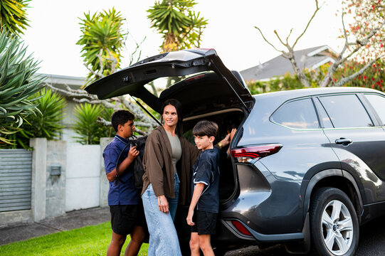 Young Maori boys helping mum load bags into the car boot