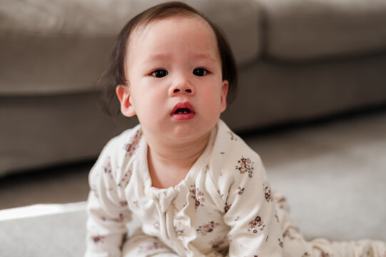 Asian baby girl crawling on the carpeted floor inside home
