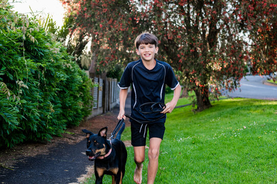 Young boy runs with his dog on a path at sunset