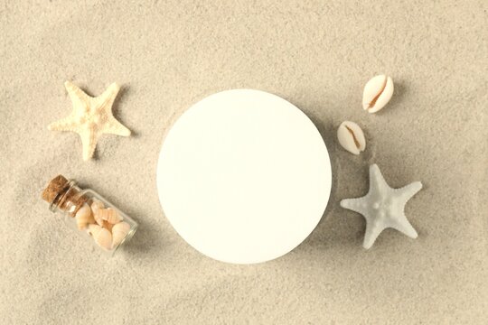 Summer seaside concept: sand shells and starfish. Various seashells with white podium on the beach sand