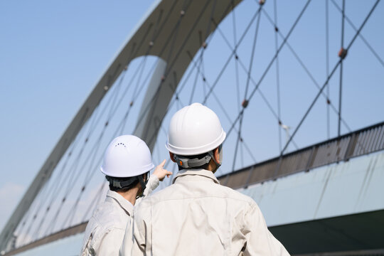 橋を指差す作業員の日本人男性