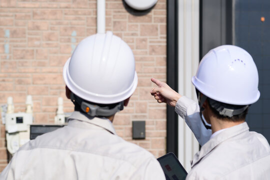 作業服を着て住宅の点検をする日本人男性