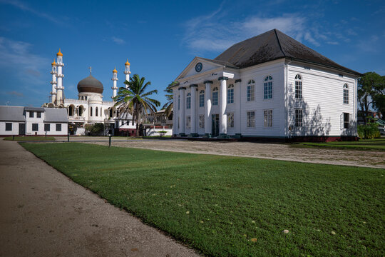View of the Neveh Shalom Synagogue and the Ahmadiyya Anjuman Isha'at Islam Mosque standing side by side under a clear blue sky in Paramaribo, Paramaribo District, Suriname.