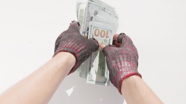 Homeless person with dirty fingerless gloves grabbing 100 dollar bills from white surface. High angle view.