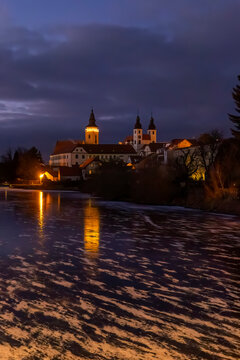 Telc cityscape reflecting on frozen water at twilight