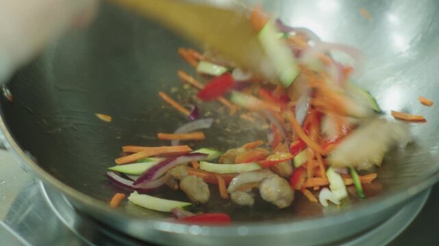 Frying vegetables in a hot iron deep frying pan. Asian cuisine. Wok frying.