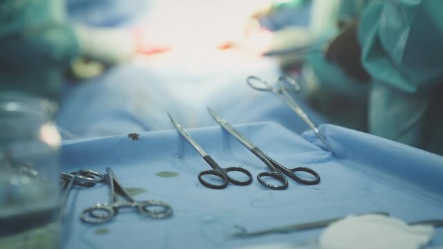 Close up medical scissors forceps on operation table surgery tools equipment innovative surgical instruments in operating room details three unrecognizable surgeons operate patient medicine health