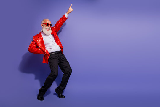 Senior man with red sequin jacket dances and points up in a vibrant party scene against a purple background