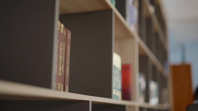Student hand selecting and taking book from library bookshelf