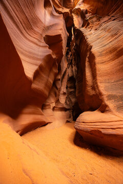 View of the wavy sandstone walls and sandy floor of Antelope Canyon in Coconino County, Arizona, United States.