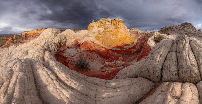 View of the unique swirling red and white sandstone formations of White Pocket under a dramatic stormy sky in Coconino County, Arizona, United States.