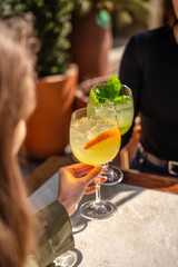 Obraz premium Friends toasting fresh citrus cocktails in warm sunlight