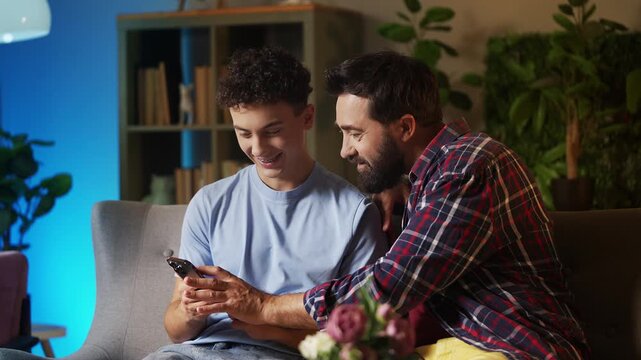 Happy teenage boy and his father choosing a travel destination on phone