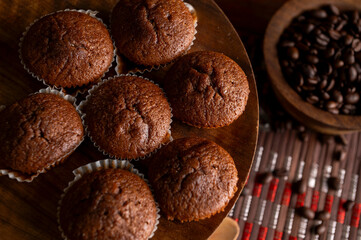 Fototapeta premium Homemade chocolate and cocoa muffins with coffee baked on a wooden board, traditional sweet chocolate bar pastry 