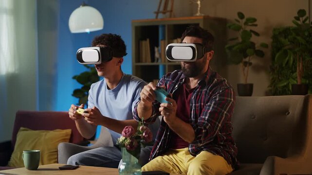 Excited father and his teen son in VR headsets playing video game at home