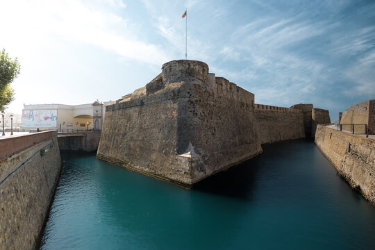 View of the historic Royal Walls of Ceuta and the navigable moat with turquoise water under a bright blue sky Ceuta, Ceuta, Spain.