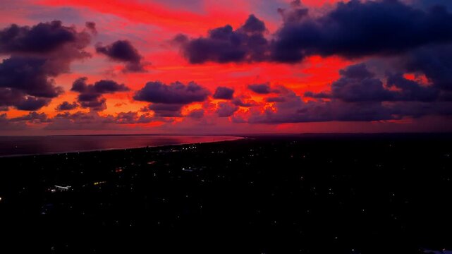Stunning 4K horizontal aerial view of a dramatic red and orange sunset over the Pangandaran coast.