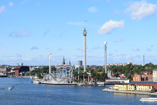 Panorama of Gr&ouml;na Lund amusement park and Stockholm waterfront, Sweden, September 2015. The shot shows various roller coasters and drop towers against a blue sky. 