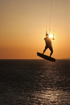 View of a kitesurfer silhouette jumping against the setting sun over the sea in Tarifa, Andalusia, Spain.