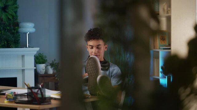 Teenage boy texting on cellphone instead of doing homework, procrastination