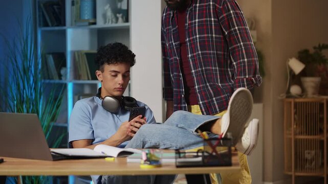 Father scolding teenage son for playing video game on phone instead of study