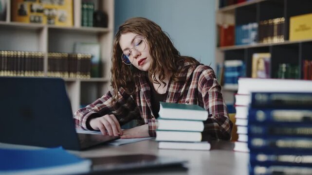 Tired female student falling asleep while studying in the library