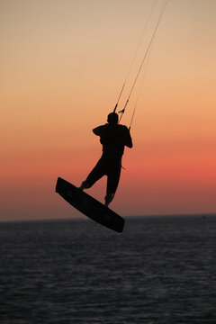 View of a kiteboarder silhouette jumping over the sea against a warm sunset sky in Tarifa, Andalusia, Spain.