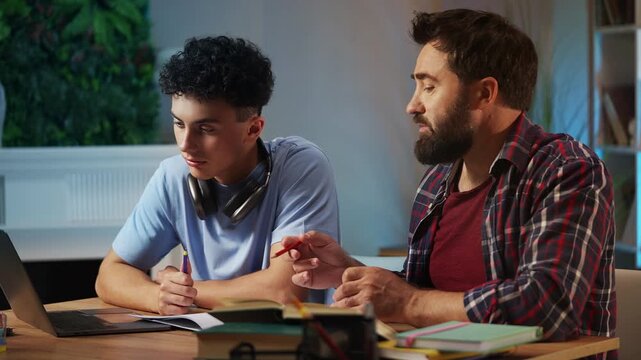 Father helping his adolescent son with homework, explaining material at home