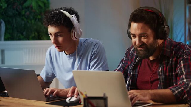 Joyful teen boy and his dad celebrating video game victory, bumping fists