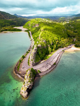 Aerial view of Maconde Viewpoint along the coastal road of Mauritius, featuring dramatic cliffs, winding road and turquoise waters of the Indian Ocean
