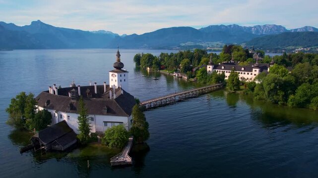 Austria Schloss Ort castle aerial 4K. Close up cinematic drone video in morning light with lake Traunsee reflections. White island fortress and wooden bridge in Gmunden.  travel scenery
