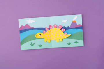Paper cut stegosaurus dinosaur on prehistoric landscape background volcano clouds hills. Ideal for elementary education kid craft tutorial creative hobby workshop diy blog nursery decor school project © Elena