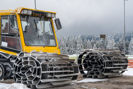 Close-up of snow groomer tracks, yellow snowcat machine covered in frost, heavy winter equipment at ski resort, slope maintenance machinery, winter technology in the mountains.