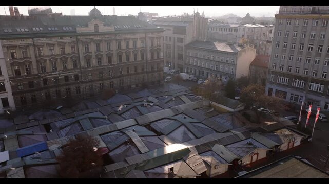 Aerial view of Stary Kleparz Market in Krakow, Poland with birds flying over historic city center rooftops.