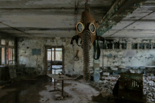 View of an old gas mask hanging from the ceiling in a derelict abandoned room with peeling paint and debris in Pripyat, Kyiv Oblast, Ukraine.
