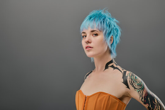 Young woman with vibrant blue hair showcasing edgy style against a neutral background