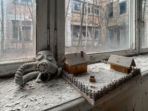 View of a gas mask and small wooden toy houses on a dusty windowsill inside an abandoned building in Pripyat, Kyiv Oblast, Ukraine.