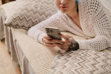 Stylish young woman lounging on a cozy couch while using her smartphone