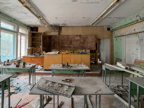 View of an abandoned classroom with decaying desks, peeling paint on the walls, and a dusty chalkboard Pripyat, Kyiv Oblast, Ukraine.