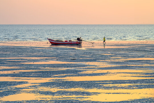 Traditional Thai fishing boat rests mudflat during low tide golden hour Wat Sri Chan Pradit pier