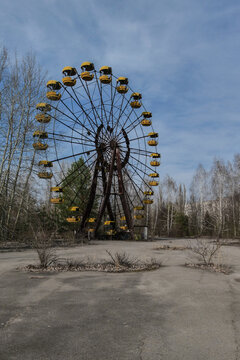 View of the iconic abandoned Ferris wheel with yellow cabins and rusty metal structure surrounded by bare trees in Pryp'yat', Kyiv Oblast, Ukraine.