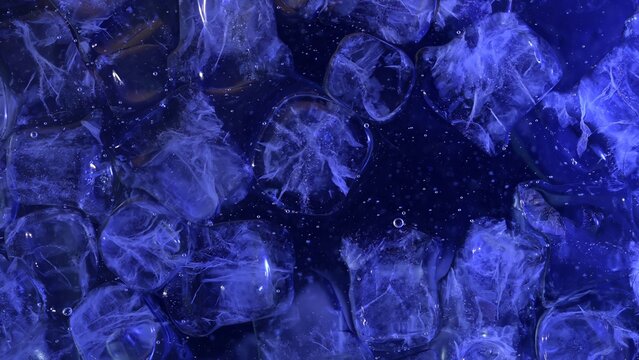 Top view of ice cubes floating on the water surface, illuminated by blue light. Concepts for beauty advertising, menu designs for bars and restaurants, cryotherapy.
