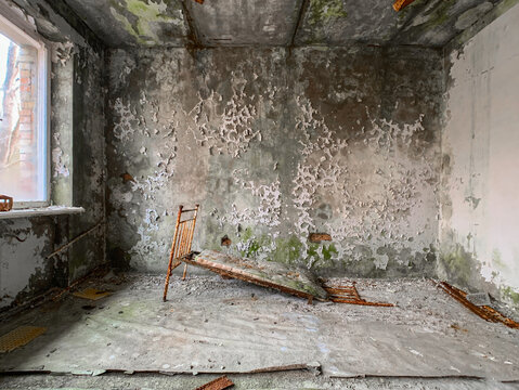 View of an abandoned room with a rusty metal bed frame and peeling paint on the walls in the Chernobyl Exclusion Zone Prypyat, Kyiv Oblast, Ukraine.