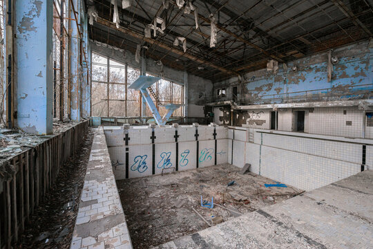 View of the abandoned Azure Swimming Pool with peeling paint, debris on the floor, and graffiti on the tiles in Pryp'yat', Kyiv Oblast, Ukraine.