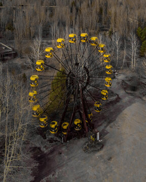 View of the iconic abandoned Ferris wheel with yellow cabins surrounded by bare trees in the Chernobyl exclusion zone Pryp'yat', Kyiv Oblast, Ukraine.