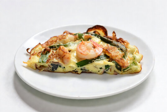 A slice of Japanese hotate omelette (shrimp omelet) is on a plate. It&rsquo;s being presented on a white surface, likely in a restaurant setting.