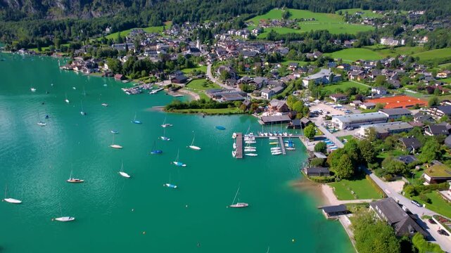 St. Gilgen Austria Drone Video, Aerial View Tilting Up from Emerald Wolfgangsee Lake with Sailing Boats to Alpine Village and High Mountains, Scenic Salzkammergut Summer Travel Destination 4K