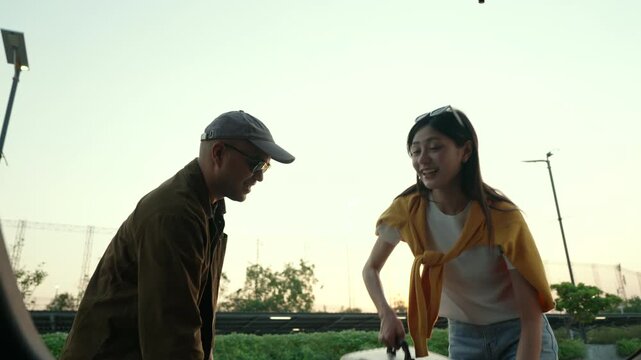  Happy young couple lifting luggage into car near airport. Travel preparation in road trip. Summer vacation and modern travel lifestyle with safe driving concept.
