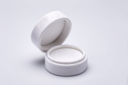 A round white velvet wedding ring box sits open with its hinged lid attached. The interior is empty and the background is pure white, creating a simple look